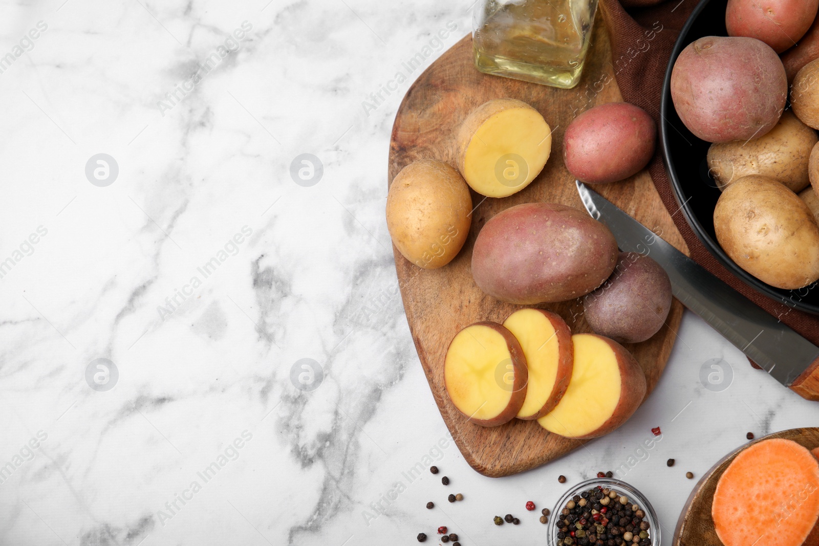 Photo of Different types of fresh potatoes on white marble table, flat lay. Space for text