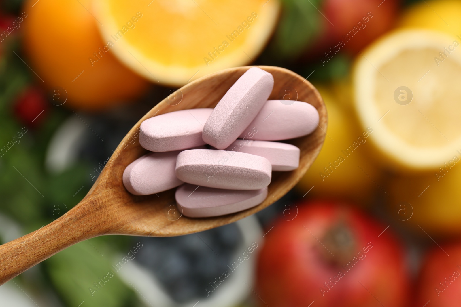 Photo of Vitamin pills in spoon over fresh fruits, top view