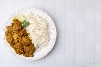 Photo of Delicious chicken curry with rice on white tiled table, top view. Space for text