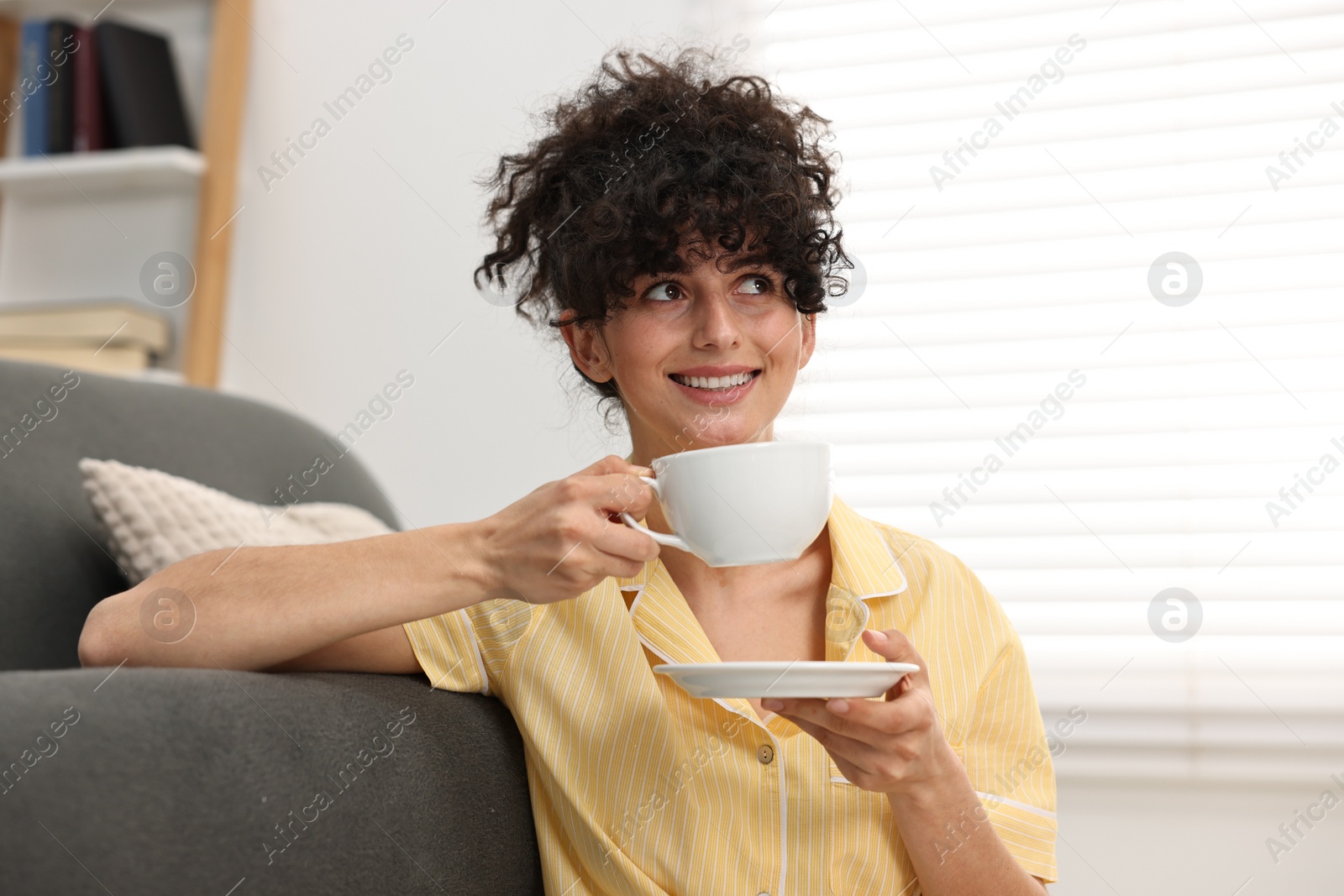 Photo of Beautiful young woman in stylish pyjama with cup of drink at home