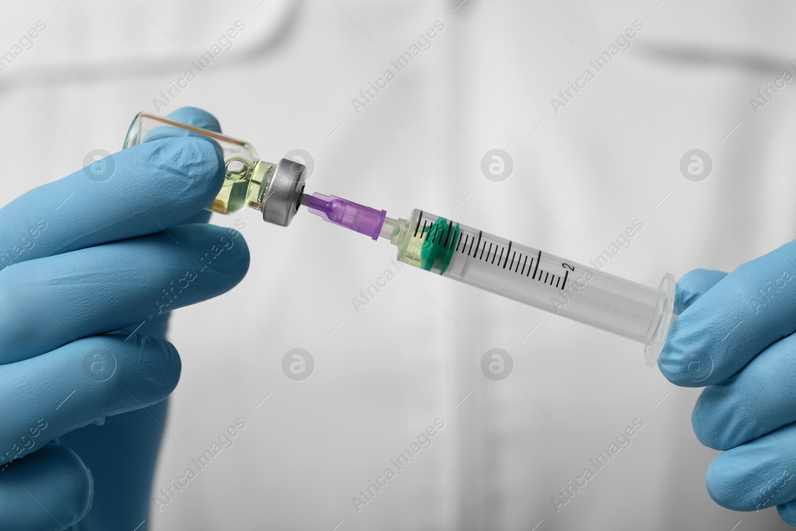 Photo of Doctor filling syringe with hepatitis vaccine from glass vial, closeup