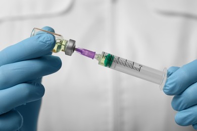 Doctor filling syringe with hepatitis vaccine from glass vial, closeup