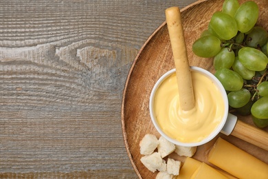 Pot of tasty cheese fondue and products on wooden table, top view. Space for text