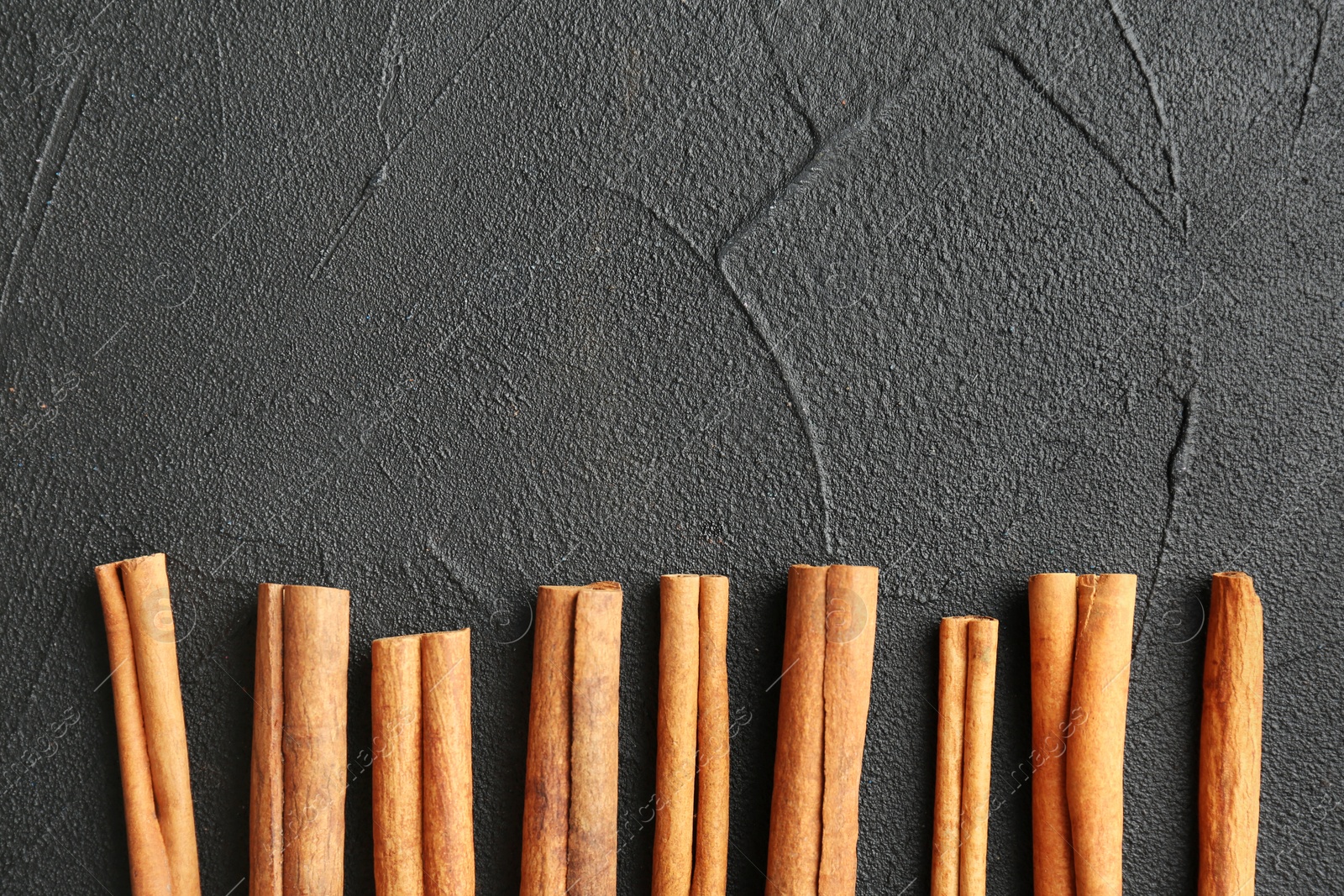 Photo of Aromatic cinnamon sticks on dark grey background