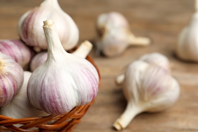 Photo of Fresh organic garlic in wicker basket, closeup