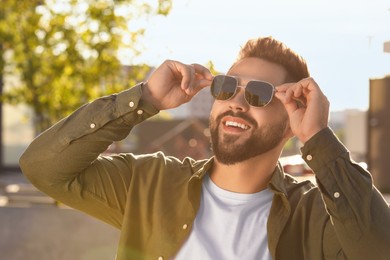 Photo of Handsome smiling man in sunglasses on city street