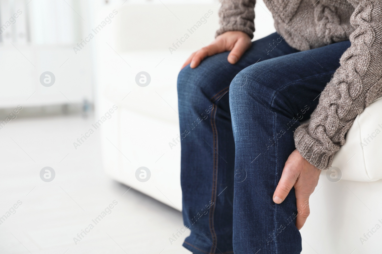 Photo of Mature man suffering from leg pain at home, closeup. Space for text