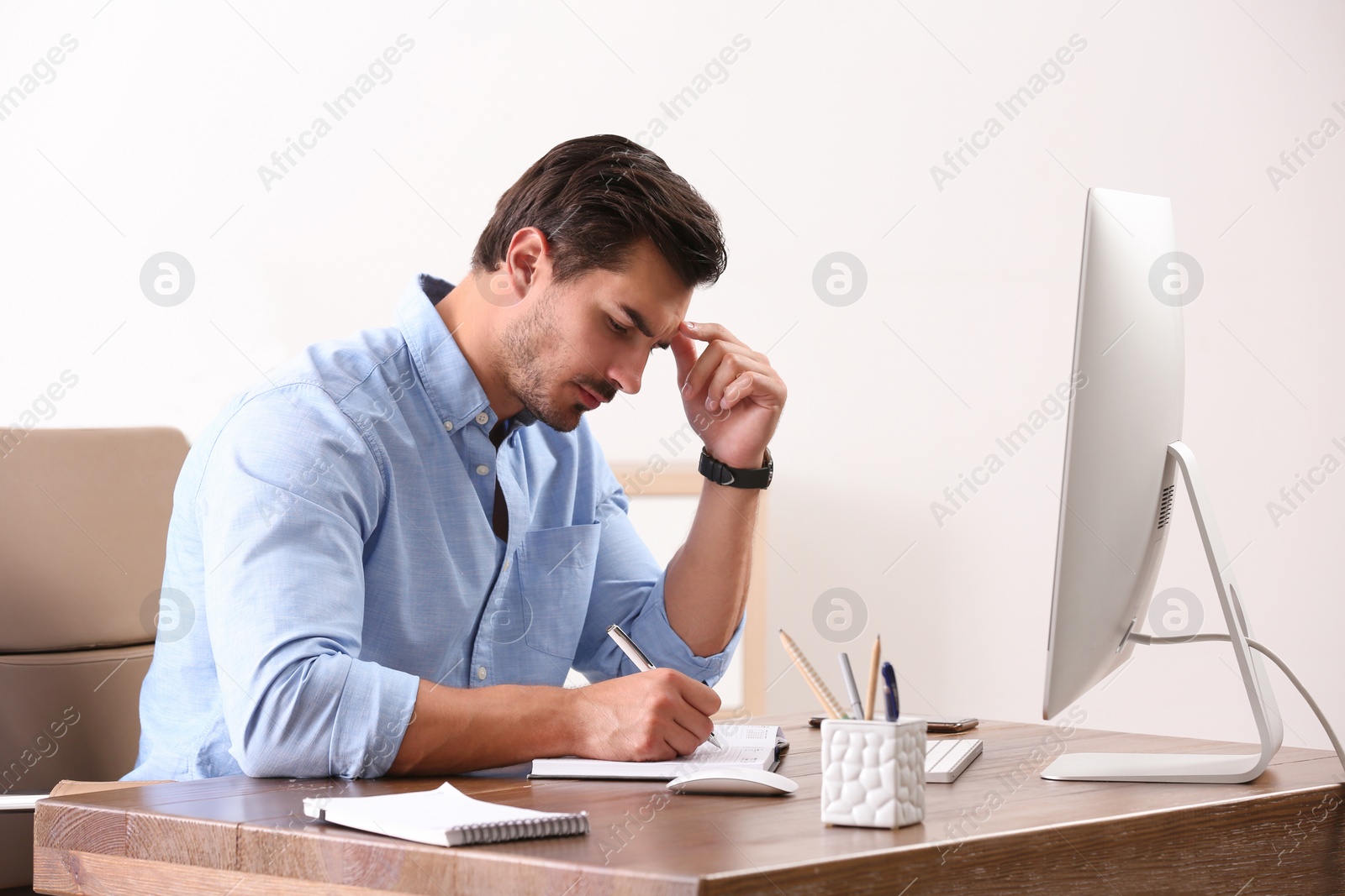 Photo of Handsome young man working with computer at table in office
