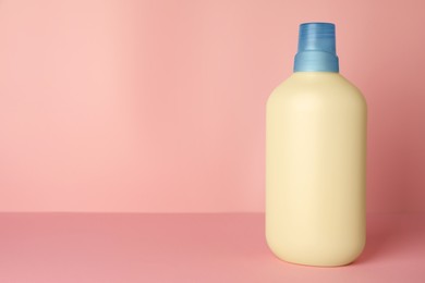 Photo of Bottle of fabric softener on pink background, space for text