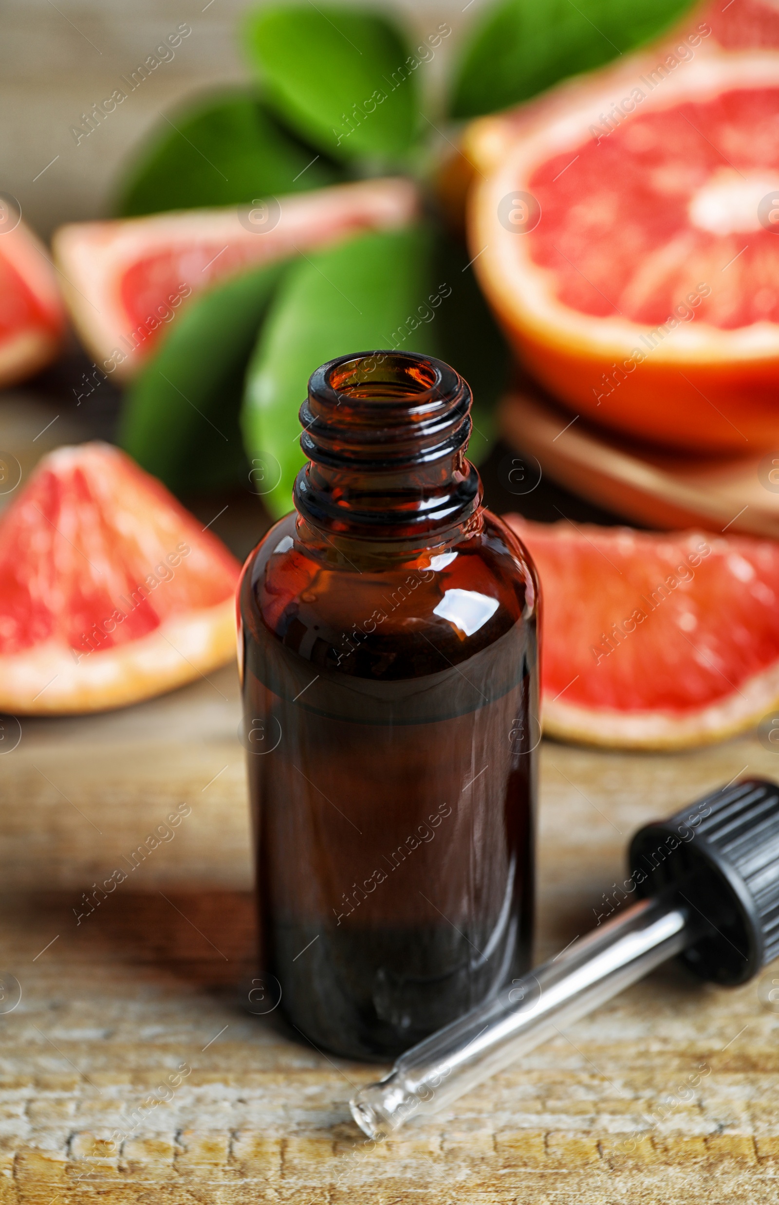 Photo of Citrus essential oil and grapefruits on wooden table