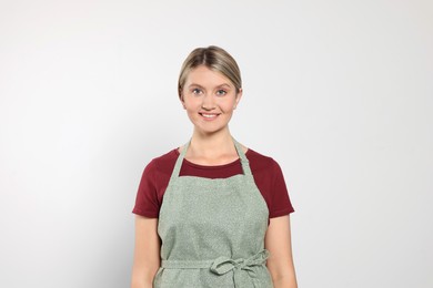 Photo of Beautiful young woman in clean apron on light grey background