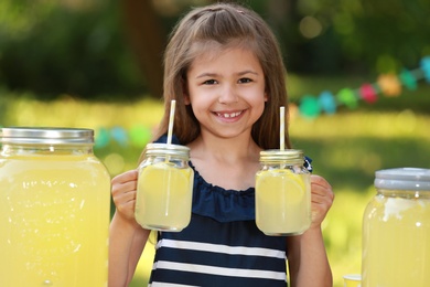 Photo of Cute little girl with natural lemonade in park. Summer refreshing drink