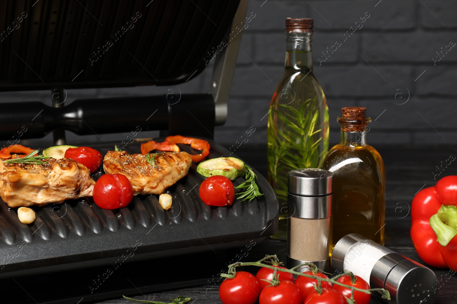 Photo of Electric grill with different products on black table