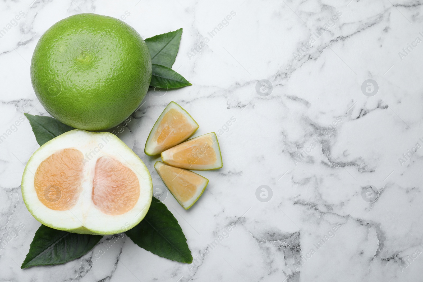 Photo of Whole and cut sweetie fruits on white marble table, flat lay. Space for text