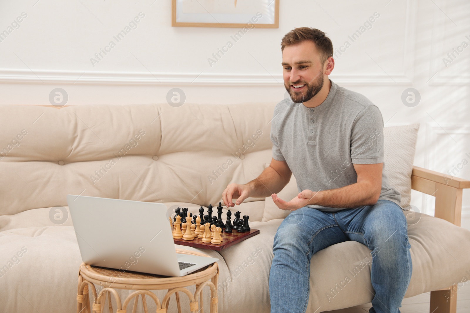 Photo of Young man playing chess with partner through online video chat at home