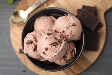 Photo of Bowl with tasty chocolate ice cream on wooden board, flat lay