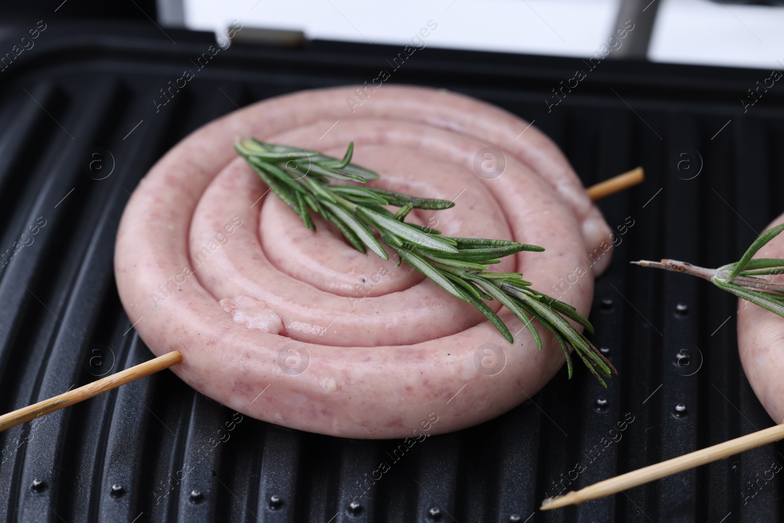 Photo of Homemade sausage and rosemary on electric grill, closeup