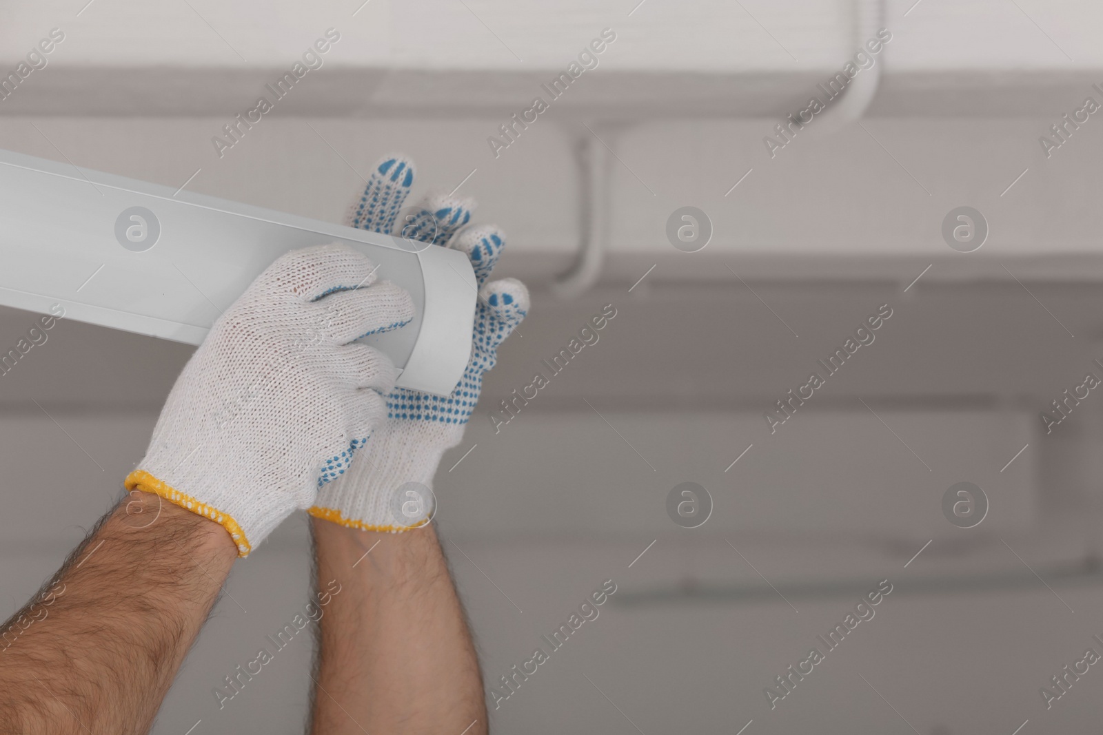 Photo of Ceiling light. Electrician installing led linear lamp indoors, closeup. Space for text