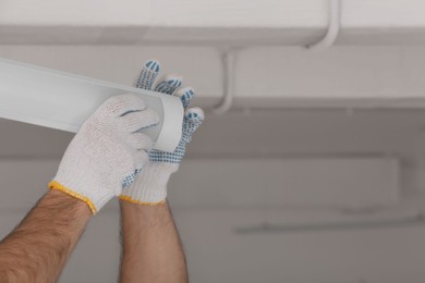 Ceiling light. Electrician installing led linear lamp indoors, closeup. Space for text