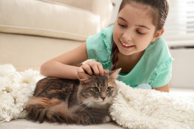 Photo of Cute little girl with cat lying on carpet at home. First pet