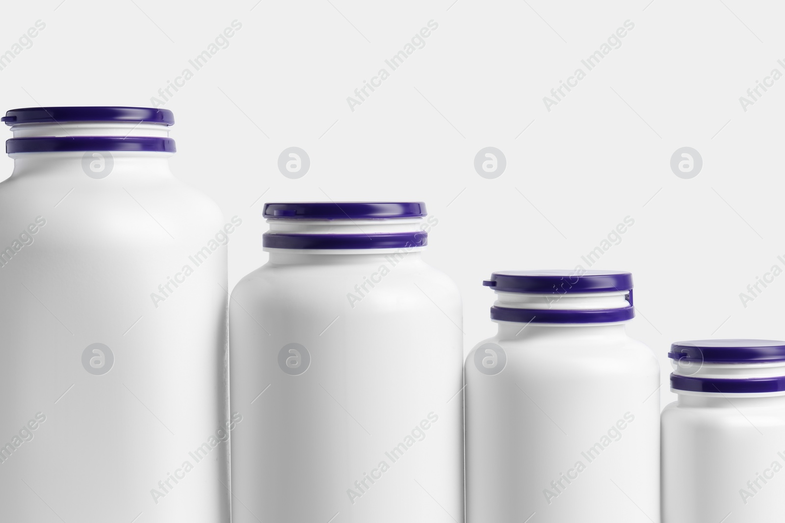 Photo of Row of different plastic medicine bottles on white background. Medicament