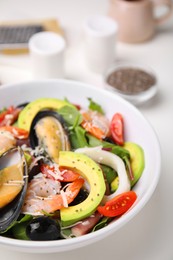 Photo of Bowl of delicious salad with seafood on white table, closeup