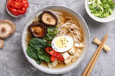 Photo of Delicious vegetarian ramen served on grey table, flat lay. Noodle soup