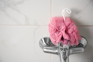 Photo of Pink shower puff on faucet in bathroom, closeup. Space for text