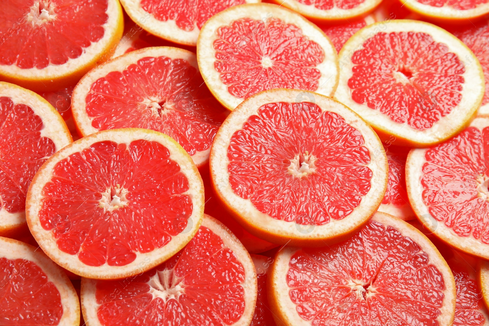 Photo of Many sliced fresh ripe grapefruits as background, closeup