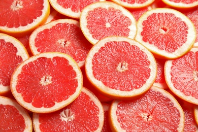 Many sliced fresh ripe grapefruits as background, closeup