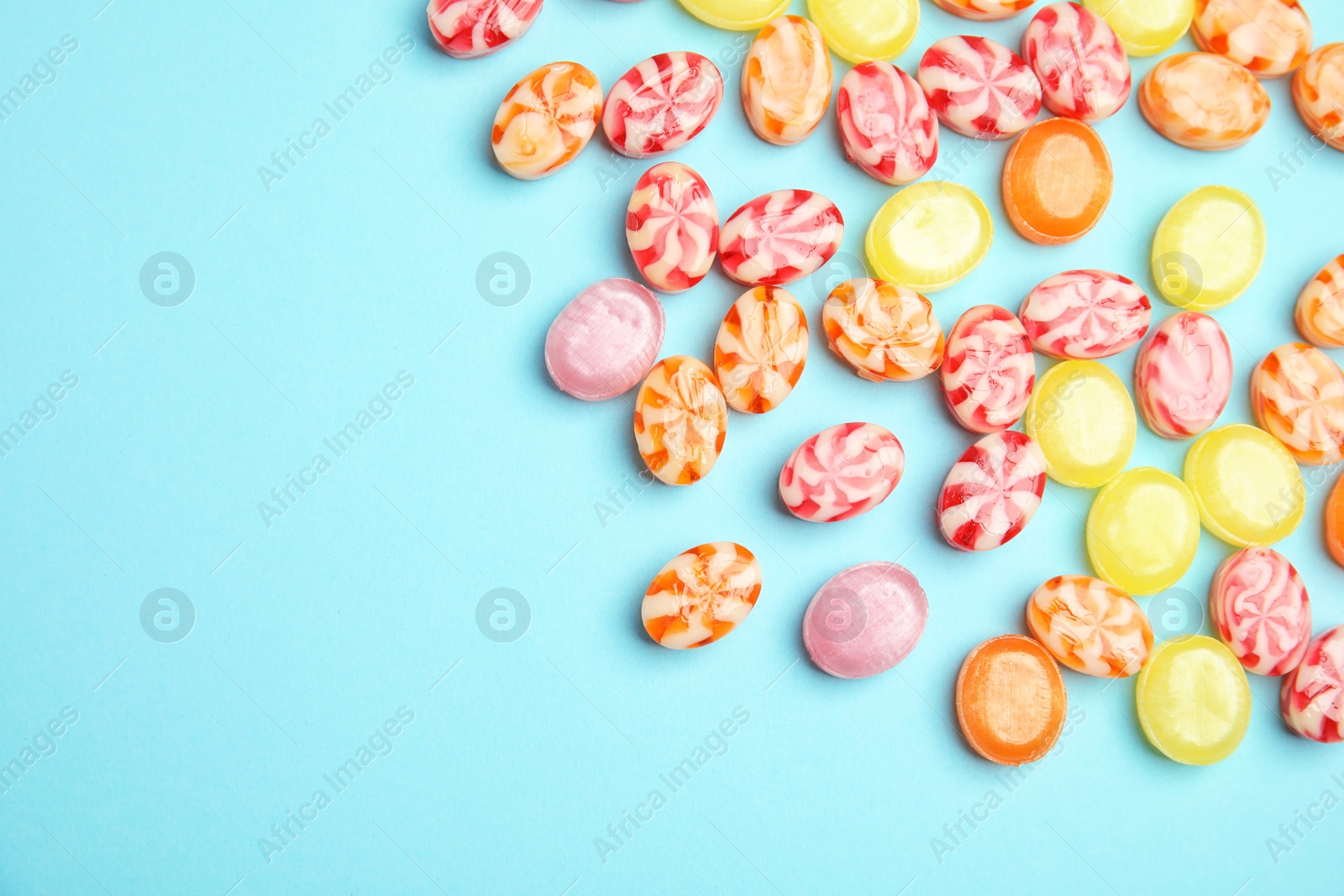 Photo of Flat lay composition with delicious colorful candies and space for text on color background