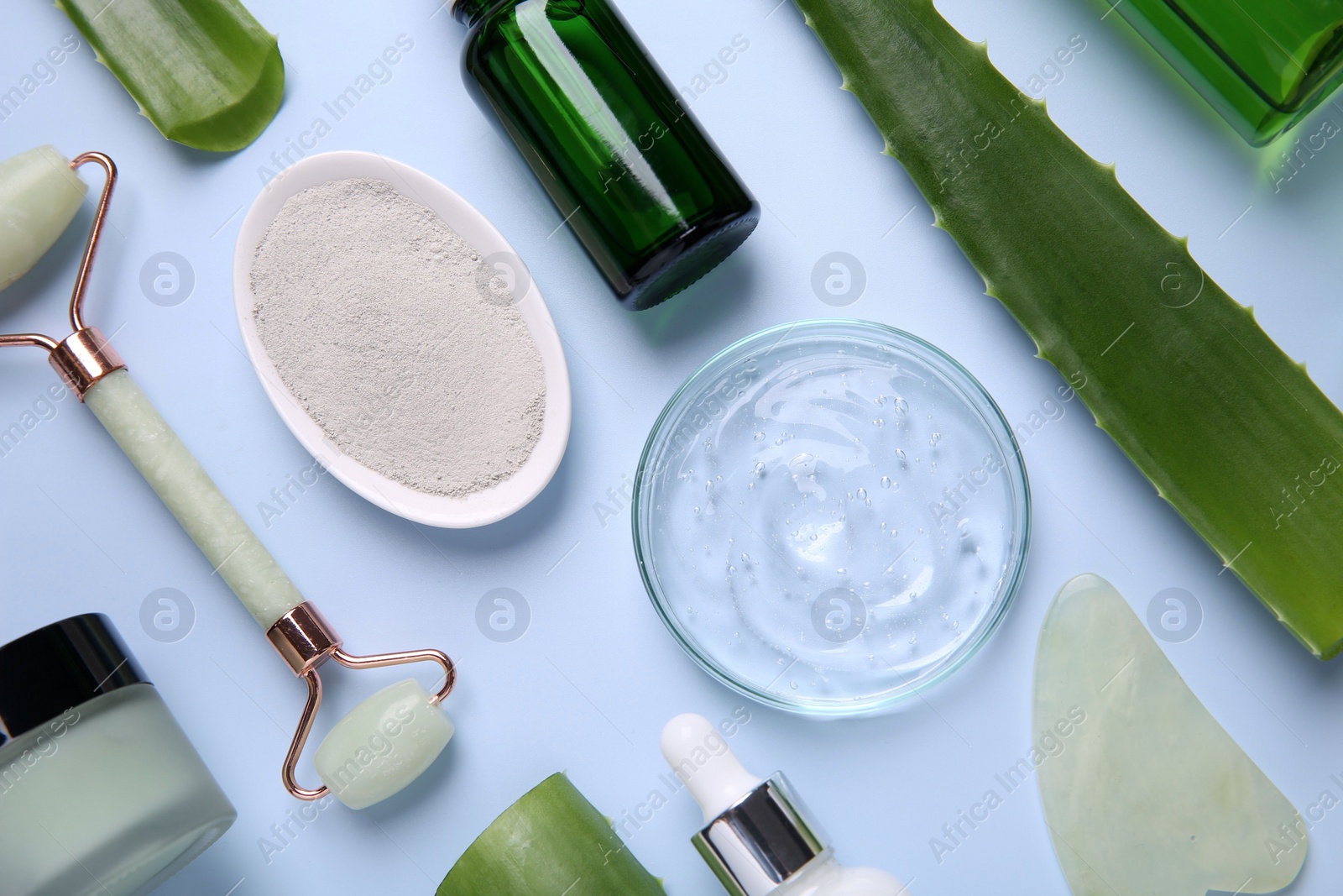 Photo of Flat lay composition with cosmetic products and cut aloe leaves on light blue background