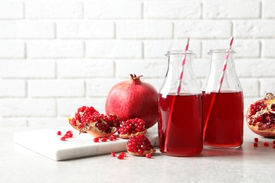 Photo of Composition with bottles of fresh pomegranate juice on table. Space for text