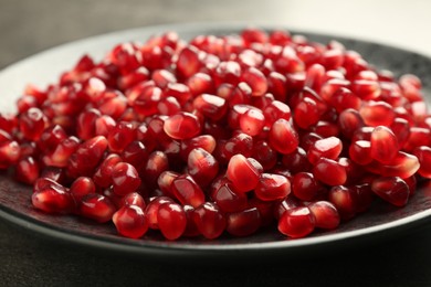 Photo of Ripe juicy pomegranate grains on grey table, closeup