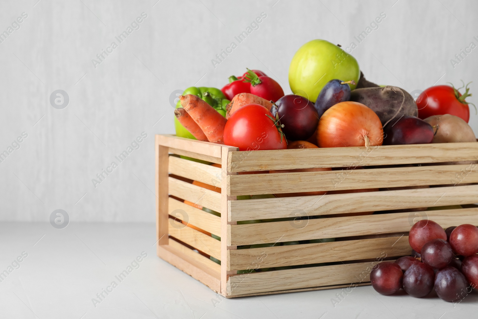 Photo of Wooden crate full of different vegetables and fruits on light table. Harvesting time