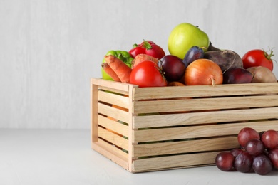 Photo of Wooden crate full of different vegetables and fruits on light table. Harvesting time