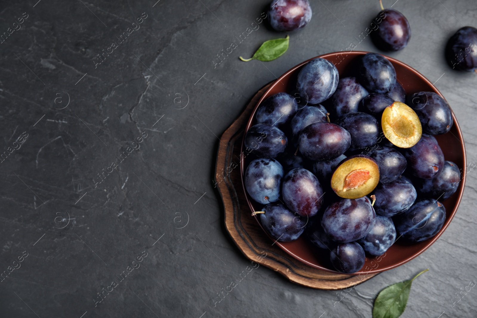 Photo of Delicious ripe plums on black table, flat lay. Space for text