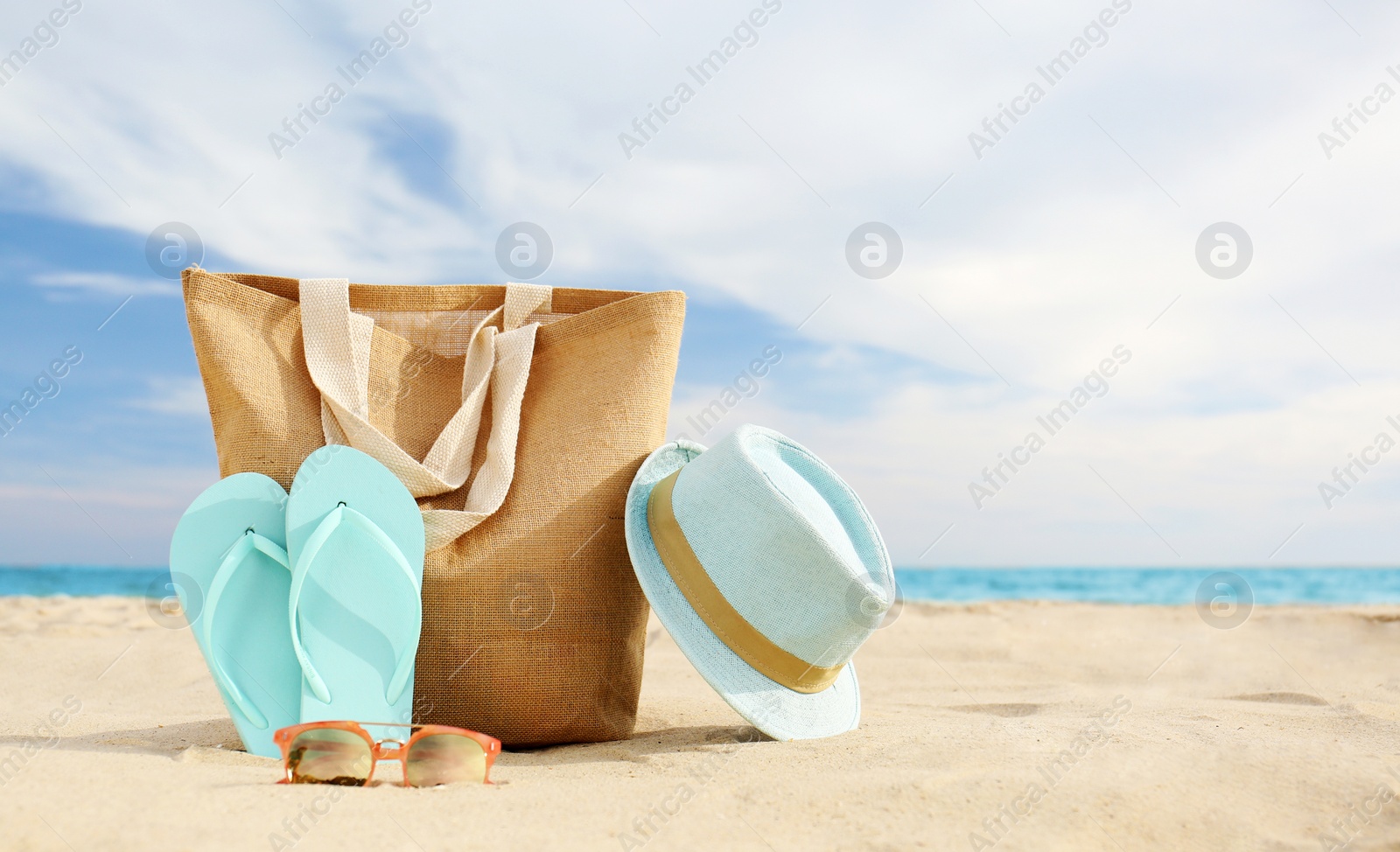 Photo of Different stylish beach objects on sand near sea