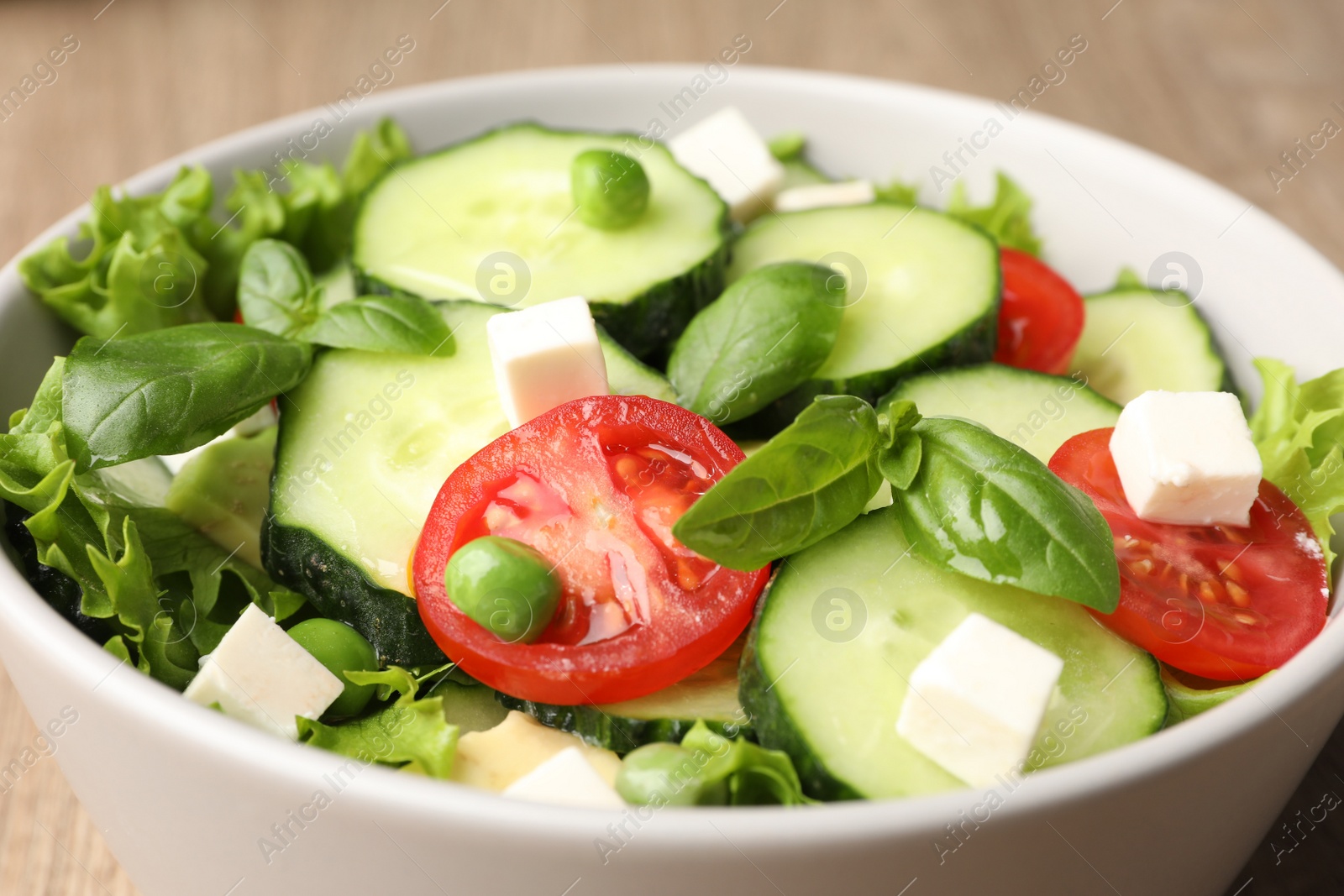 Photo of Tasty fresh salad with cucumber in bowl on table, closeup