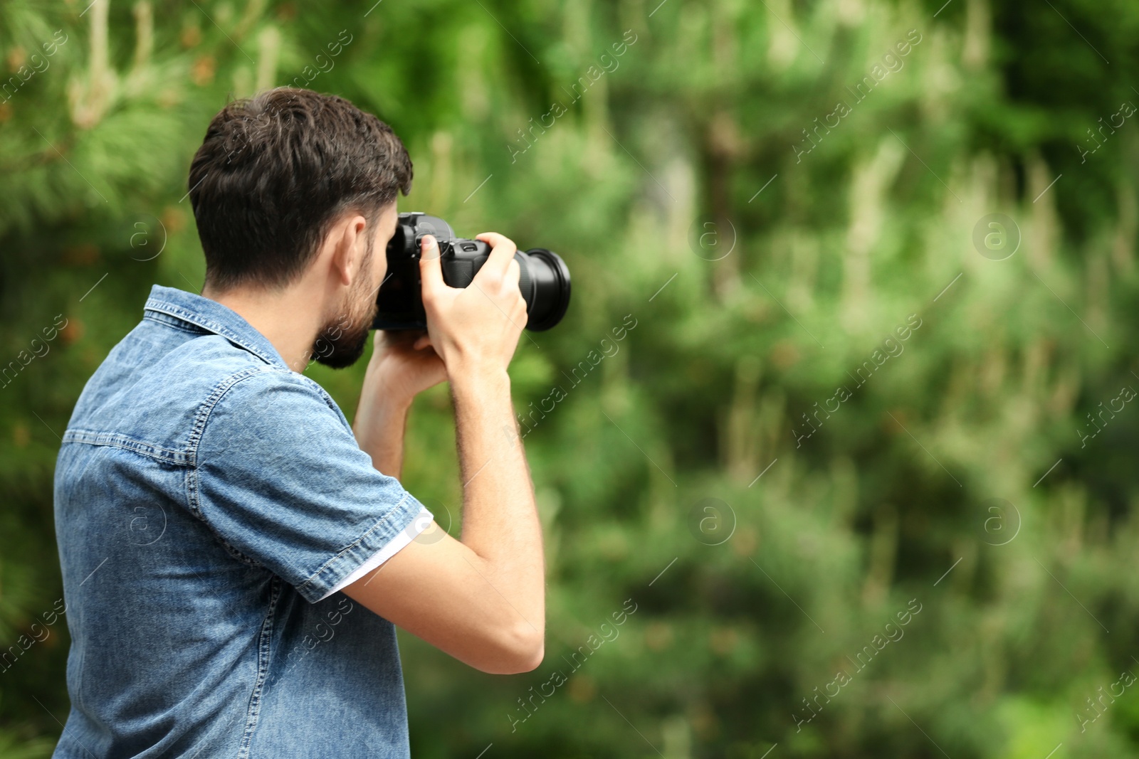 Photo of Photographer taking photo with professional camera in park. Space for text