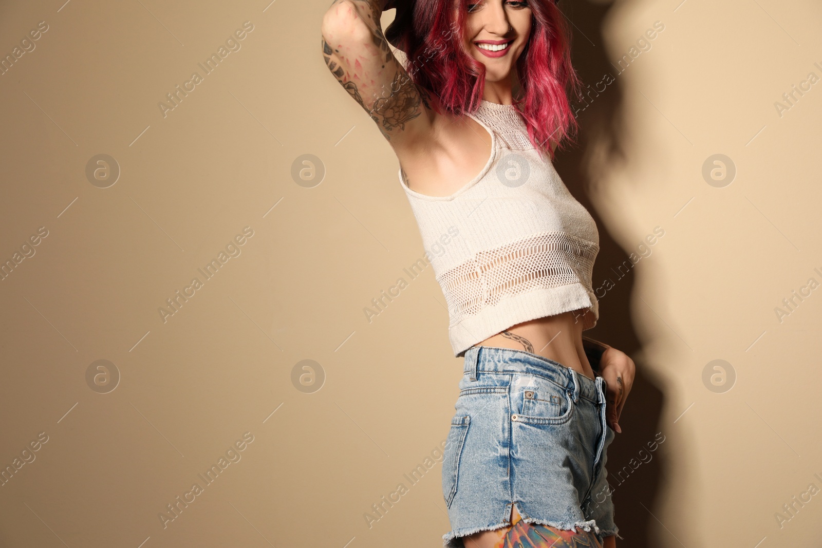 Photo of Beautiful woman with tattoos on body against beige background. Space for text