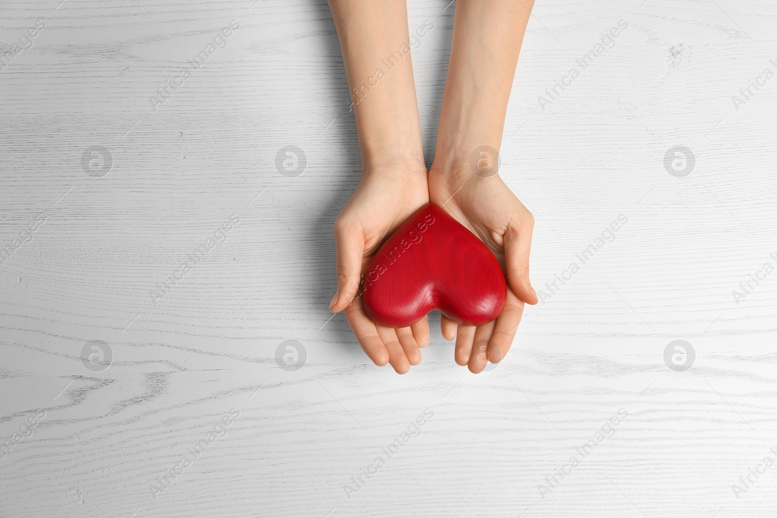 Photo of Woman holding decorative heart on white background, top view. Space for text