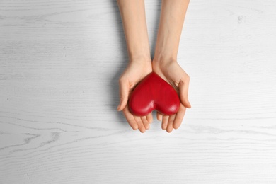 Photo of Woman holding decorative heart on white background, top view. Space for text