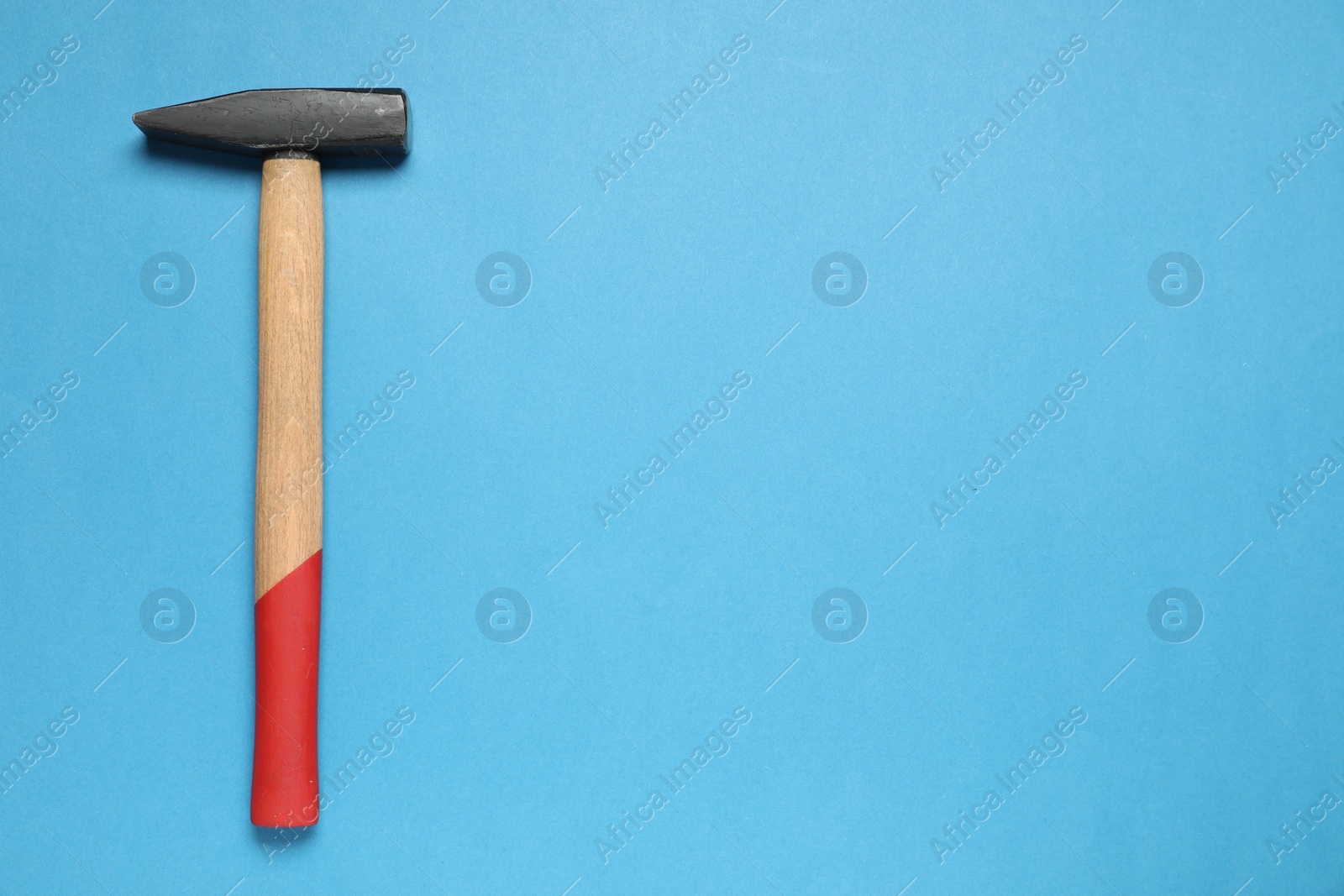 Photo of New hammer with wooden handle on light blue background, top view. Space for text