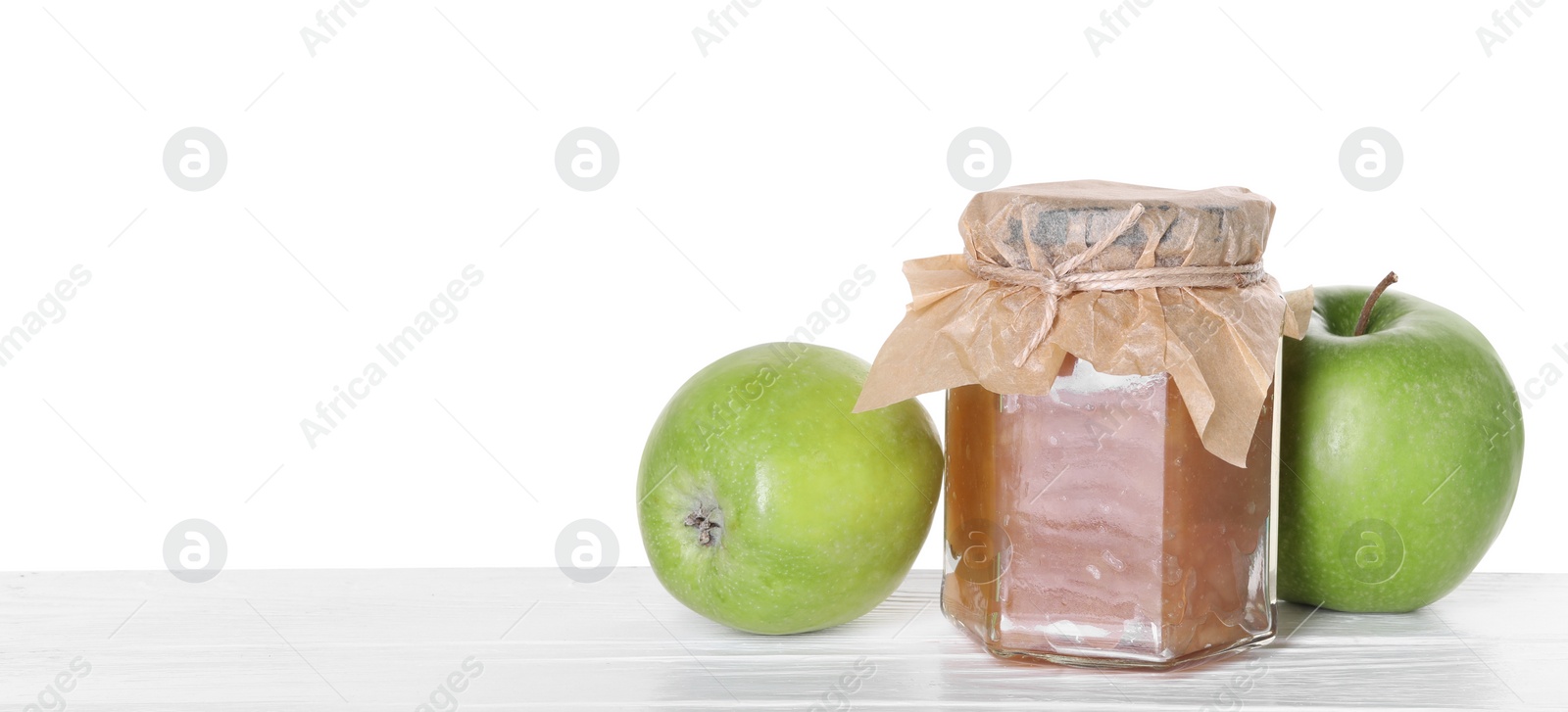 Photo of Delicious apple jam in jar and fresh fruits on wooden table against white background, space for text