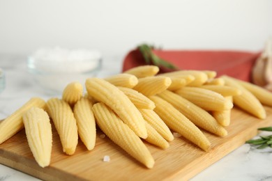 Photo of Delicious fresh baby corn cobs on wooden board, closeup