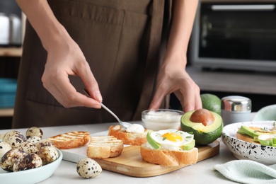 Woman preparing tasty bruschetta at light grey marble table, closeup