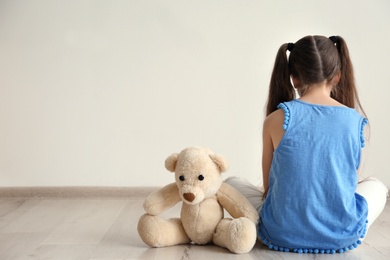 Photo of Lonely little girl sitting on floor in room. Autism concept