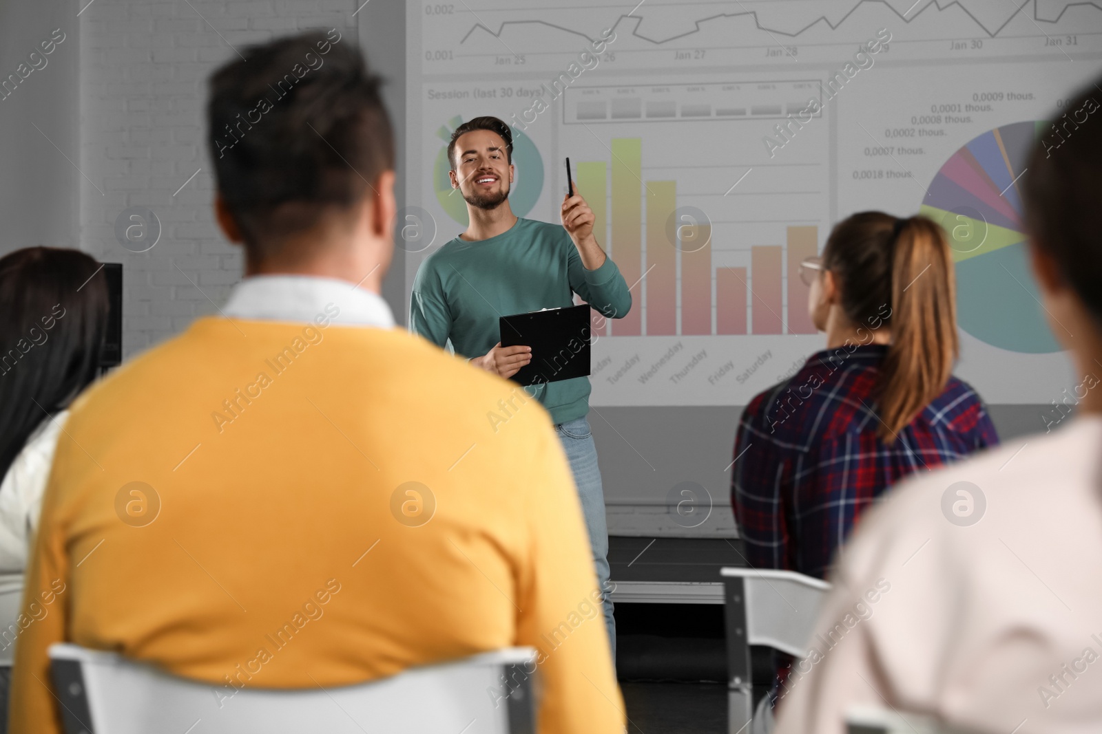 Photo of Male business trainer giving lecture in conference room with projection screen