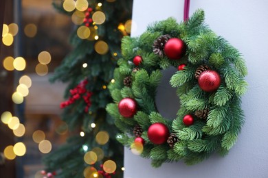 Photo of Beautiful Christmas wreath hanging on building wall outdoors, space for text
